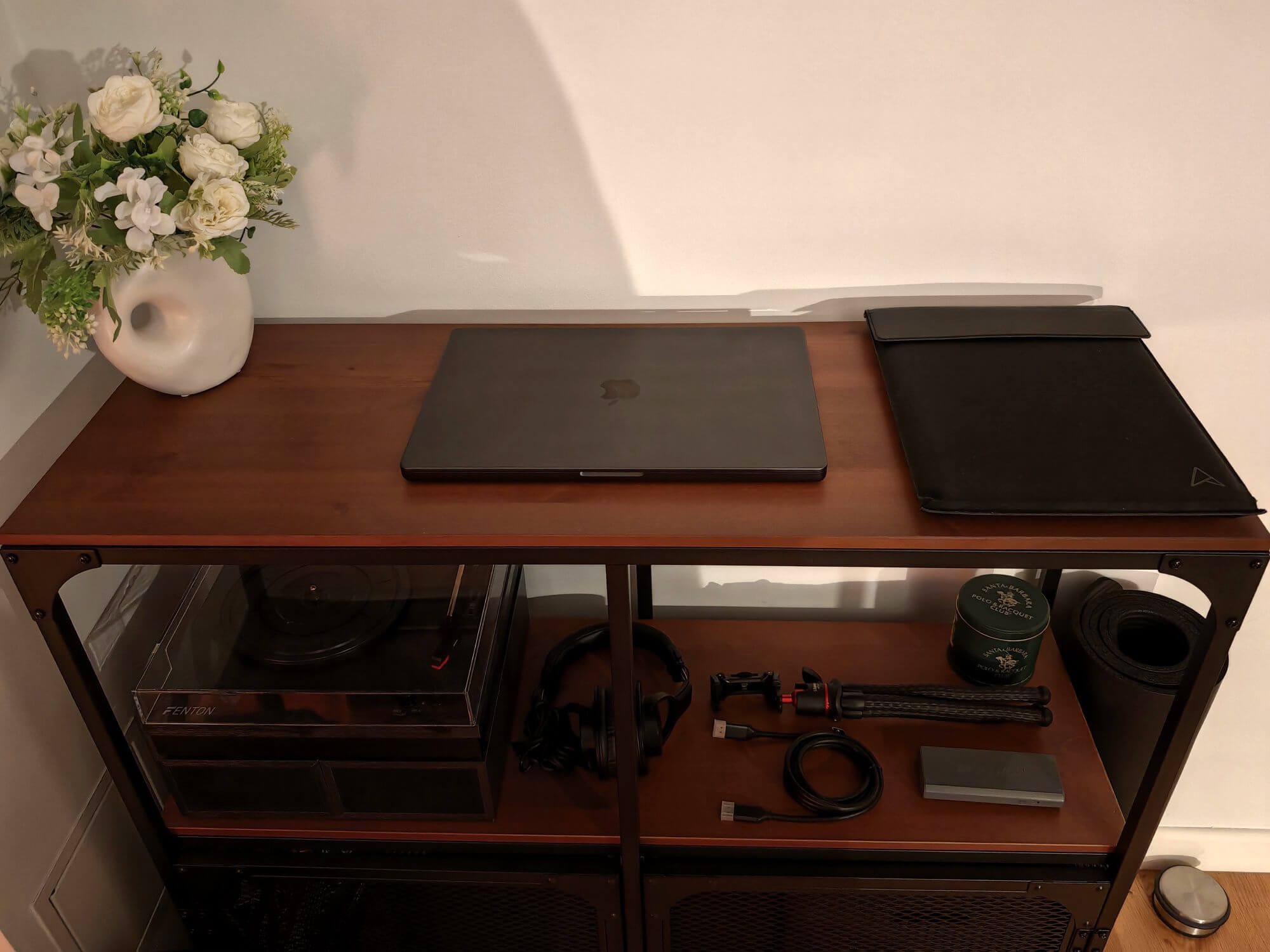 A shelf with MacBook Pro M4 Max and headphones on a wooden unit