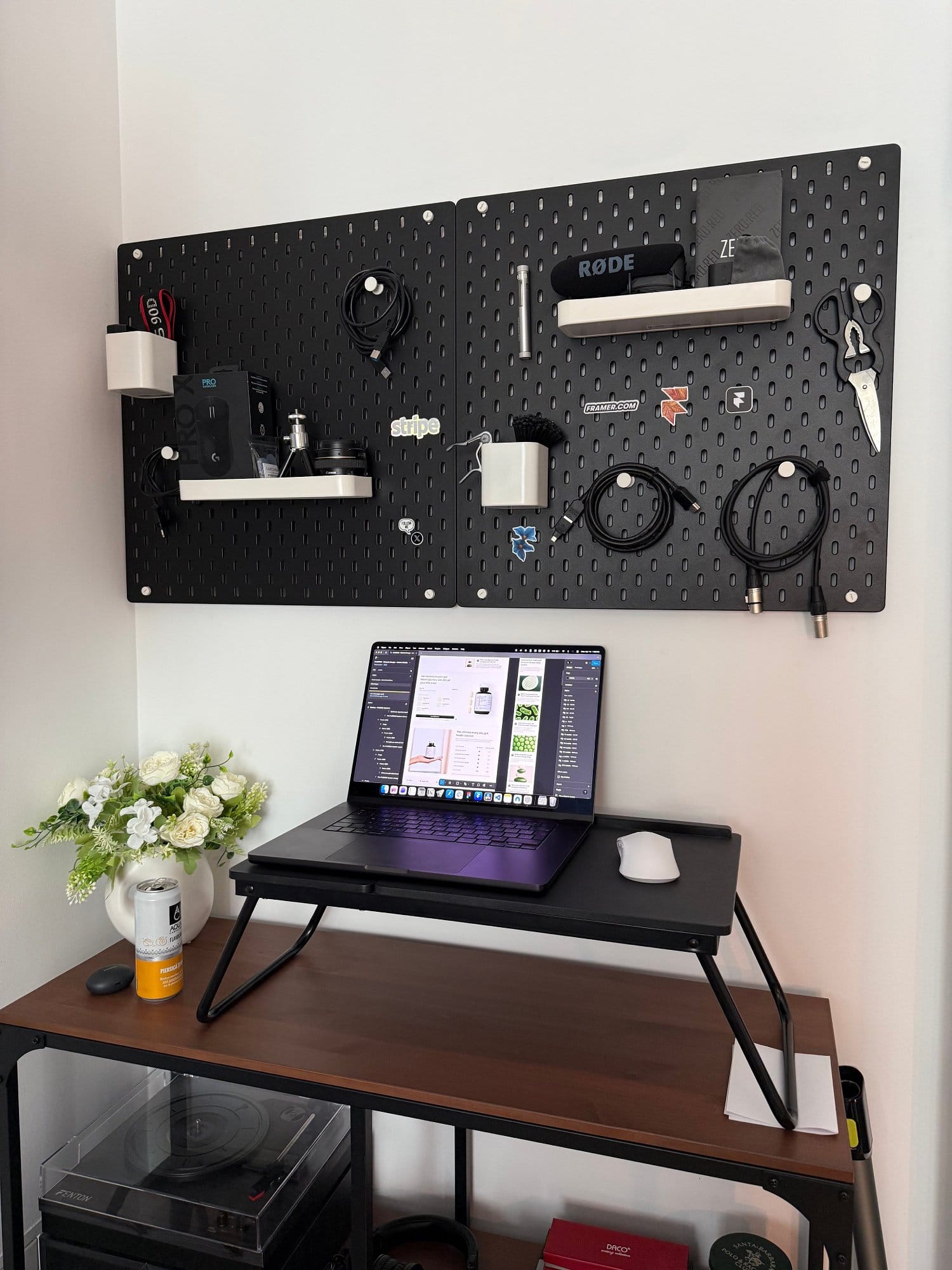A shelf with MacBook Pro M4 Max under pegboards and RØDE Procaster