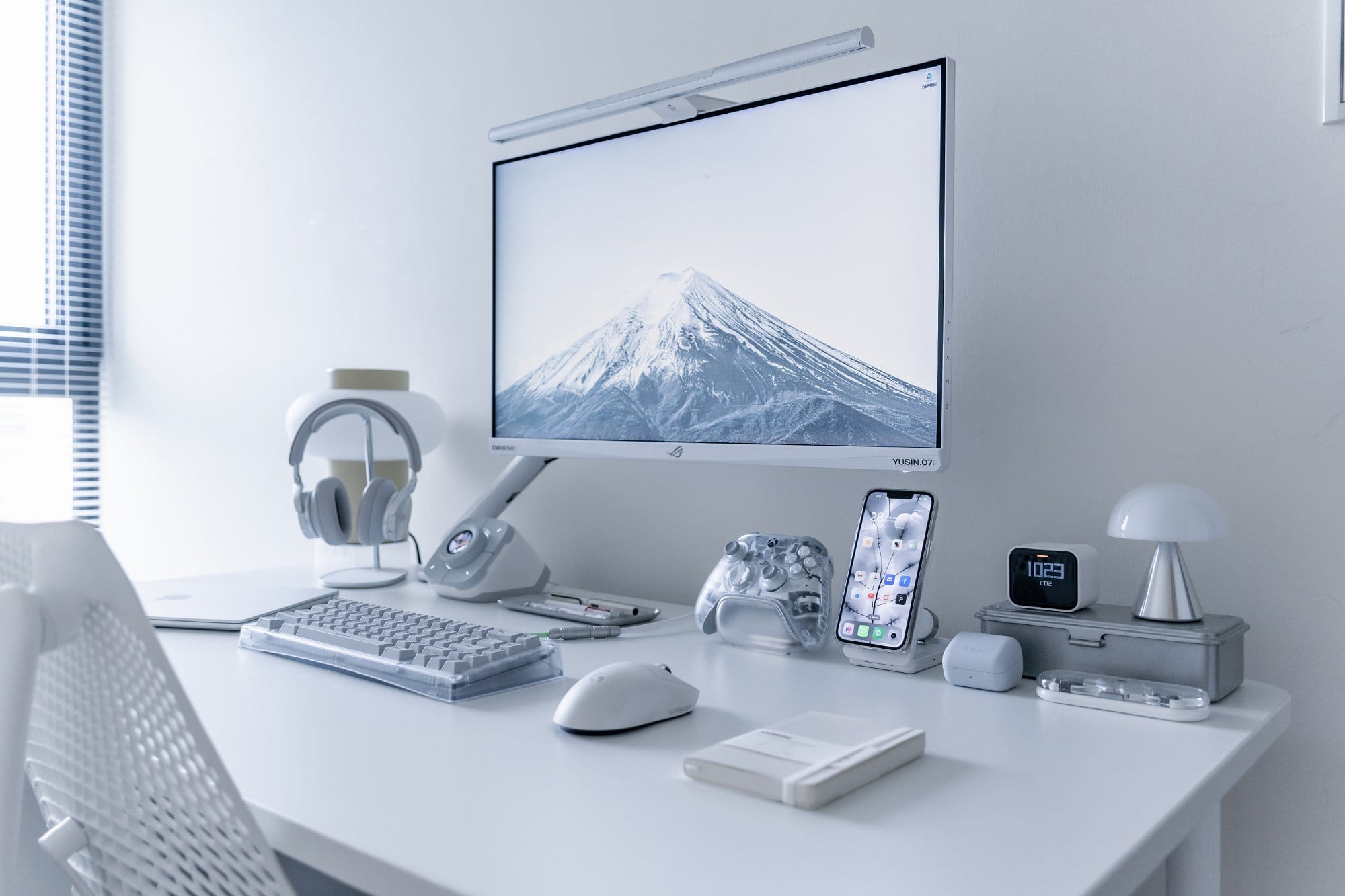 A desk setup with an ASUS ROG XG279Q-GD monitor on a Herman Miller Flo arm, MacBook Air M2 and B&O H95 headphones