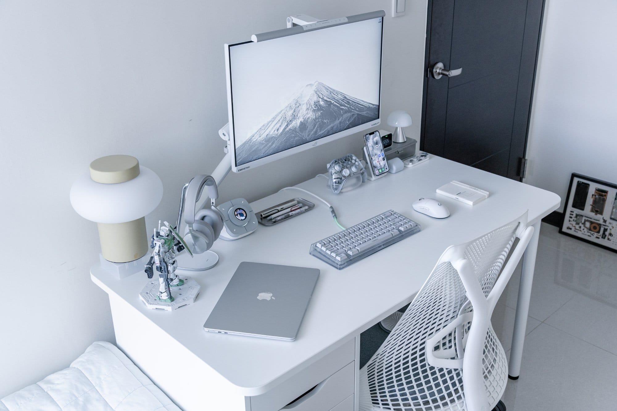 A bedroom home desk corner with an ASUS monitor, MacBook Air M2 and B&O H95 headphones
