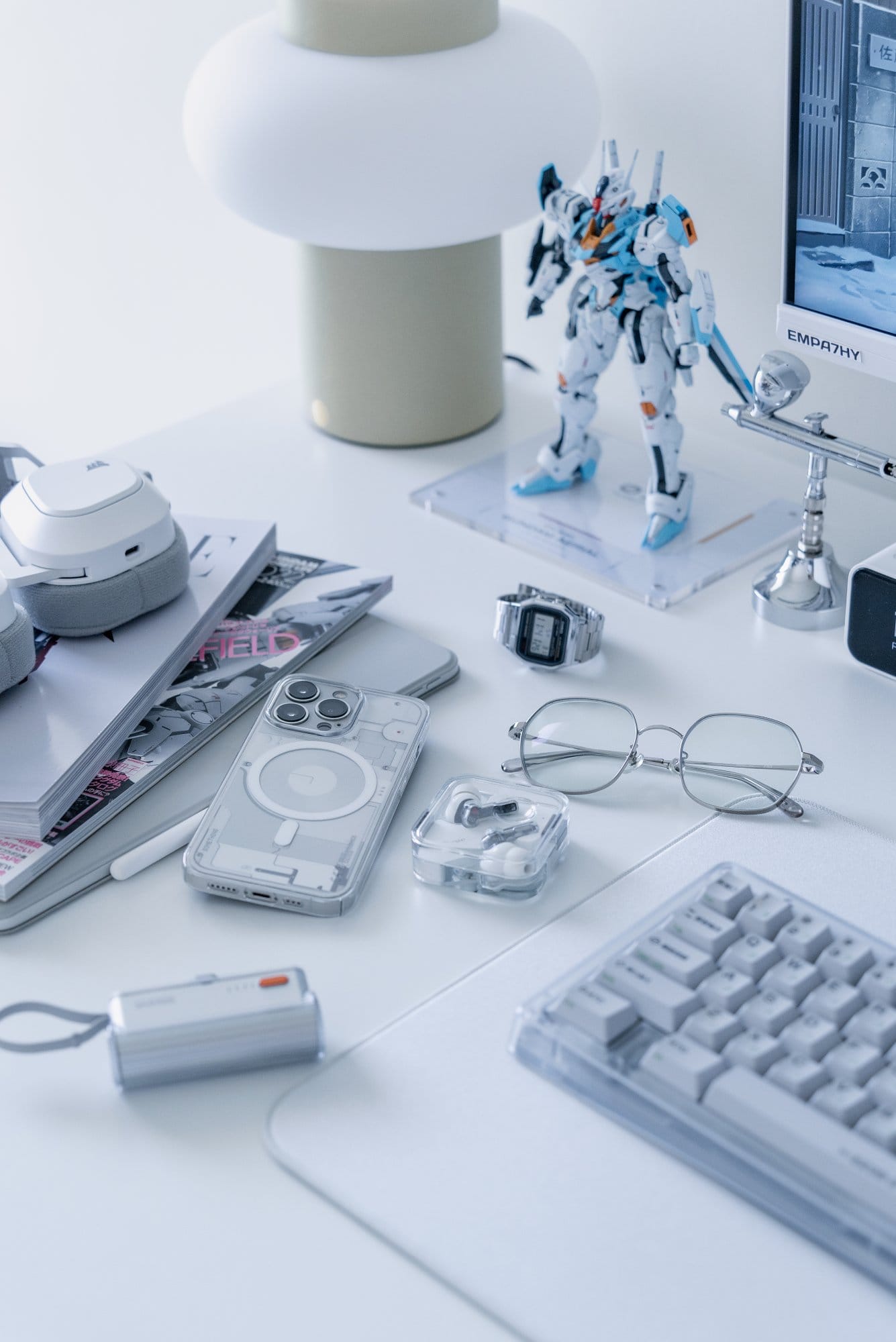 A desk with B&O H95 headphones, a MacBook Air M2 and a Gundam model under a Hübsch lamp