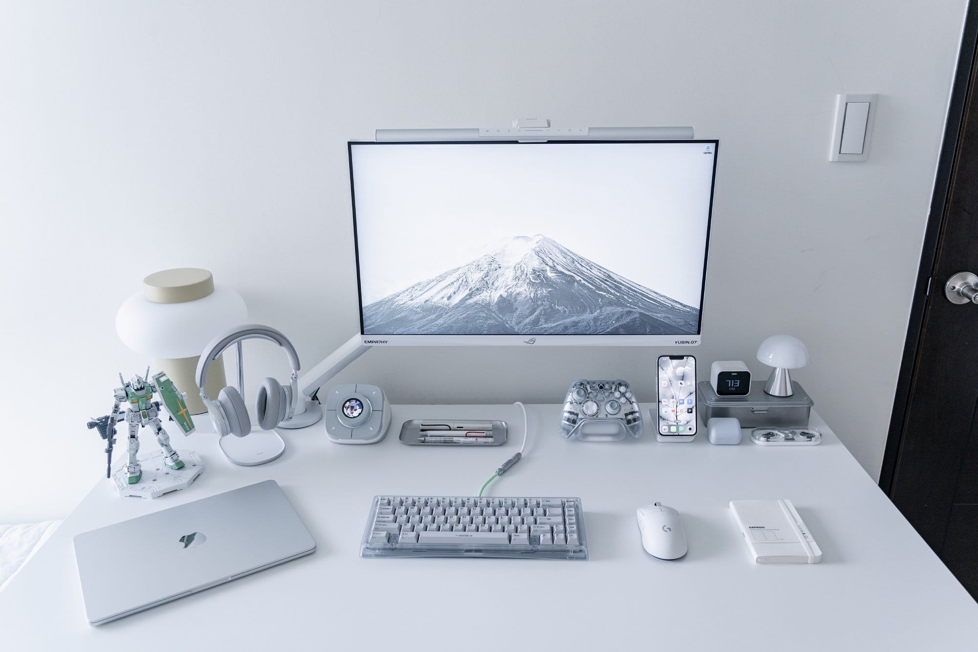 A minimalist home desk with an ASUS ROG XG279Q-GD monitor on a Herman Miller Flo arm, MacBook Air M2 and B&O H95 headphones