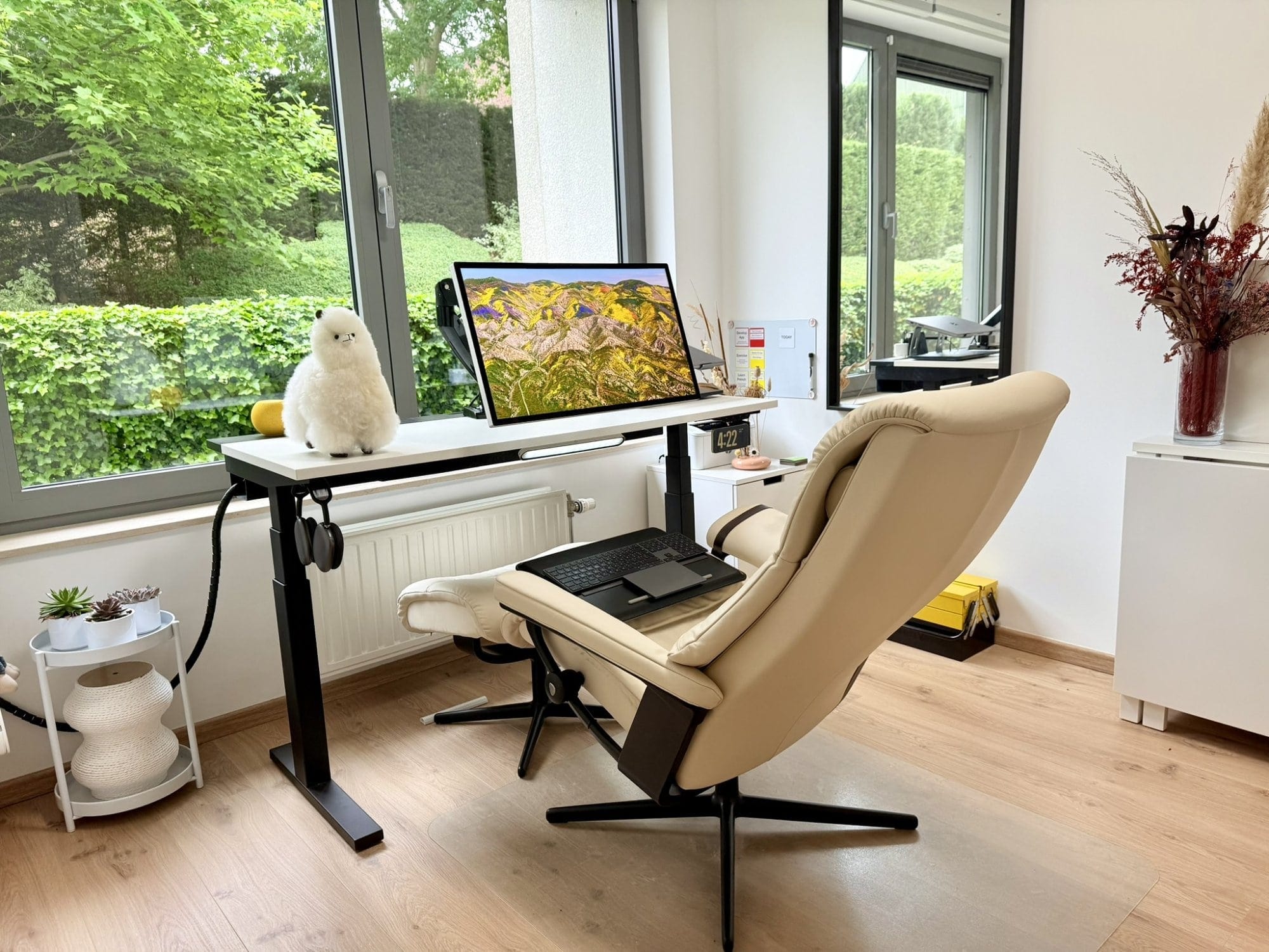 A zero gravity setup with an Apple Studio Display, MacBook Pro 16″ M1 Pro, Stressless View chair, AirPods Max, and yellow HomePod Mini by the window