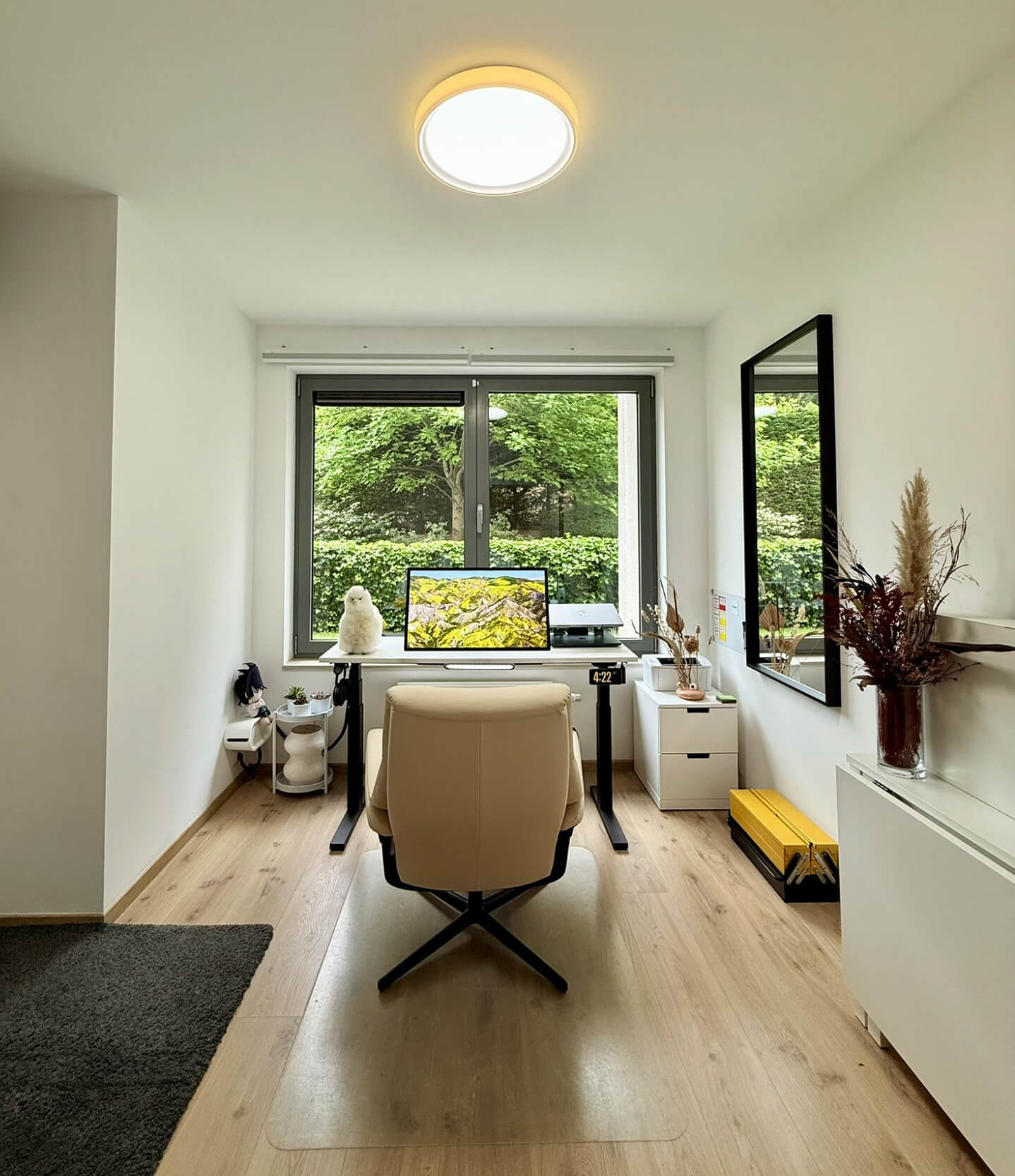 A home workspace with an Apple Studio Display, MacBook Pro 16″ M1 Pro, and Stressless View chair