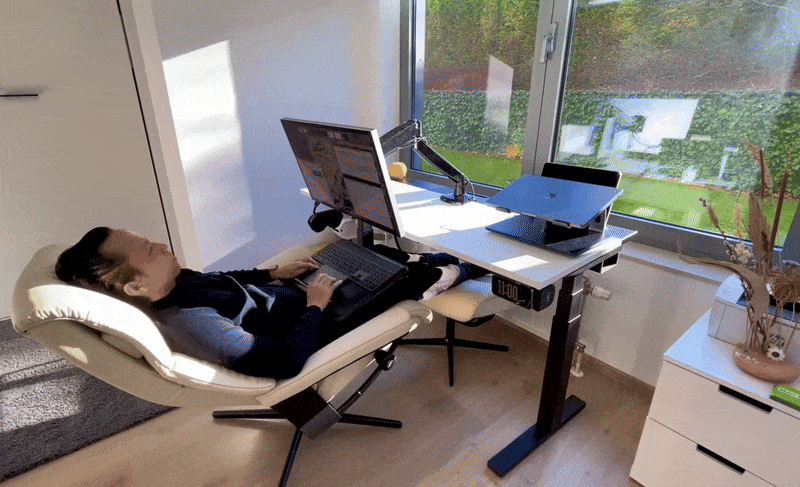 A man reclining in a Stressless View chair using an Apple Studio Display
