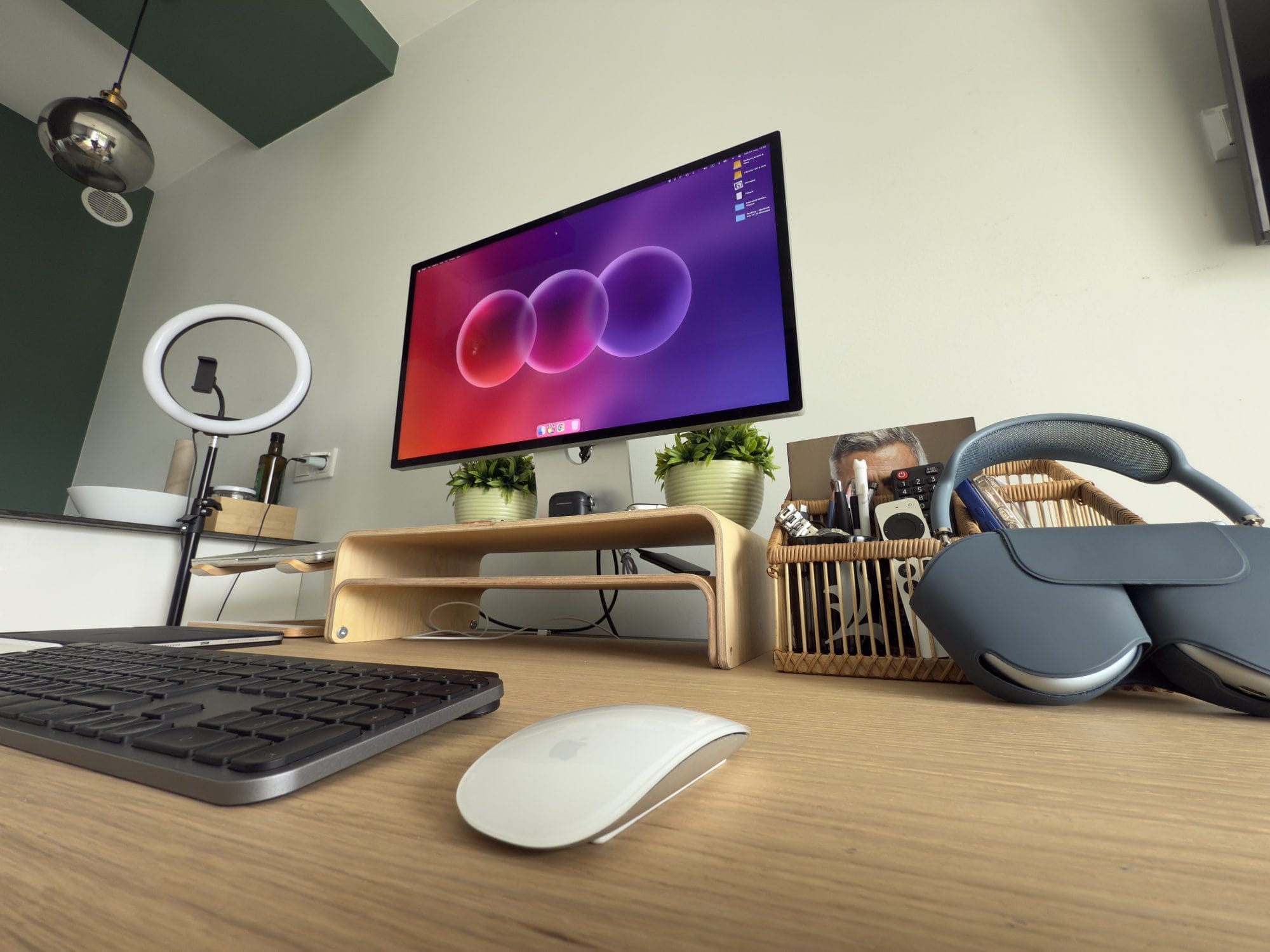 Modern home office desk setup with Apple Studio Display, wireless keyboard and mouse, AirPods Max, ring light, and organised workspace accessories