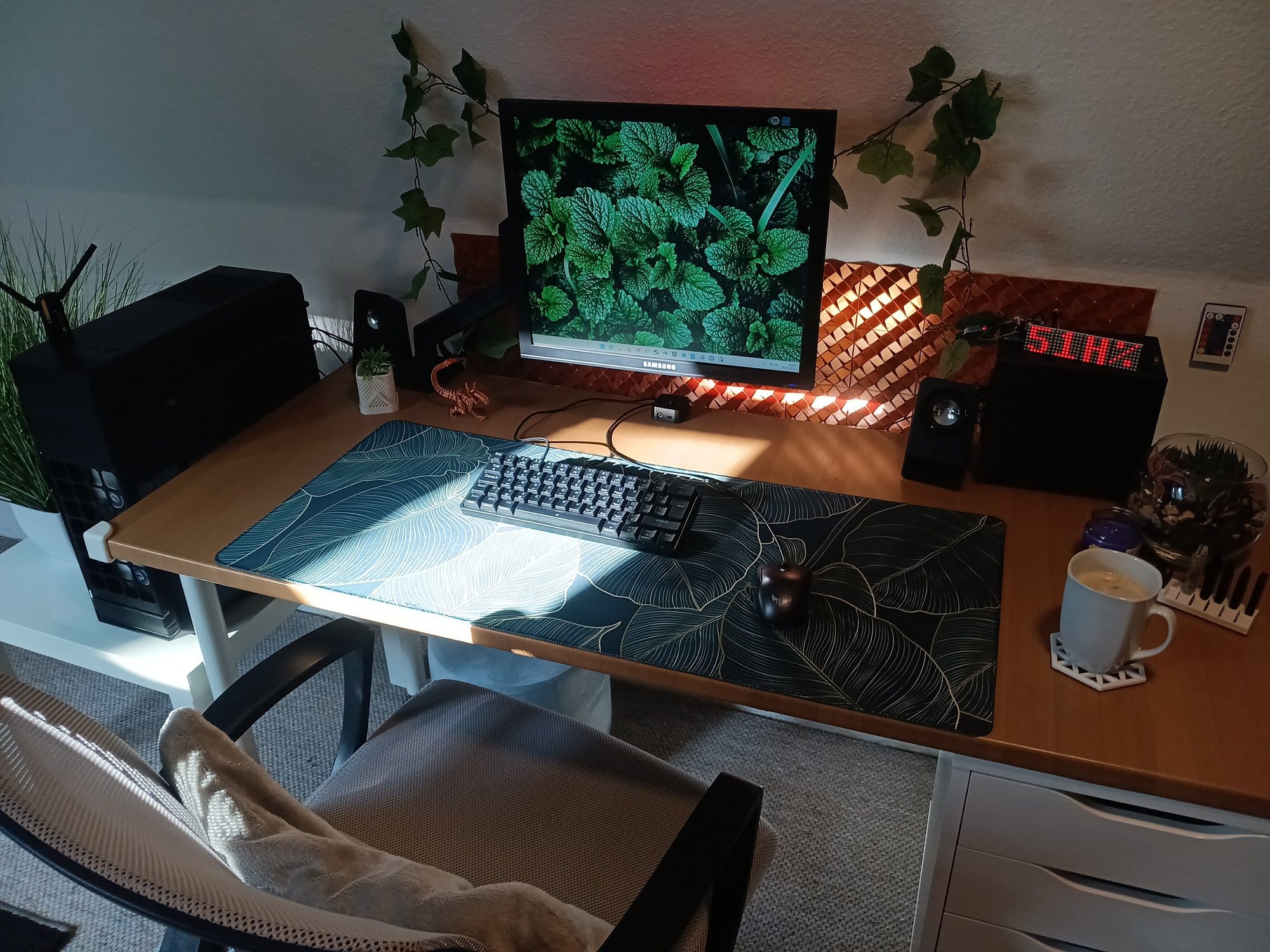minimalist desk setup with a single monitor, mechanical keyboard, ergonomic office chair, wooden desk with IKEA ALEX drawers, indoor plants, and coffee mug