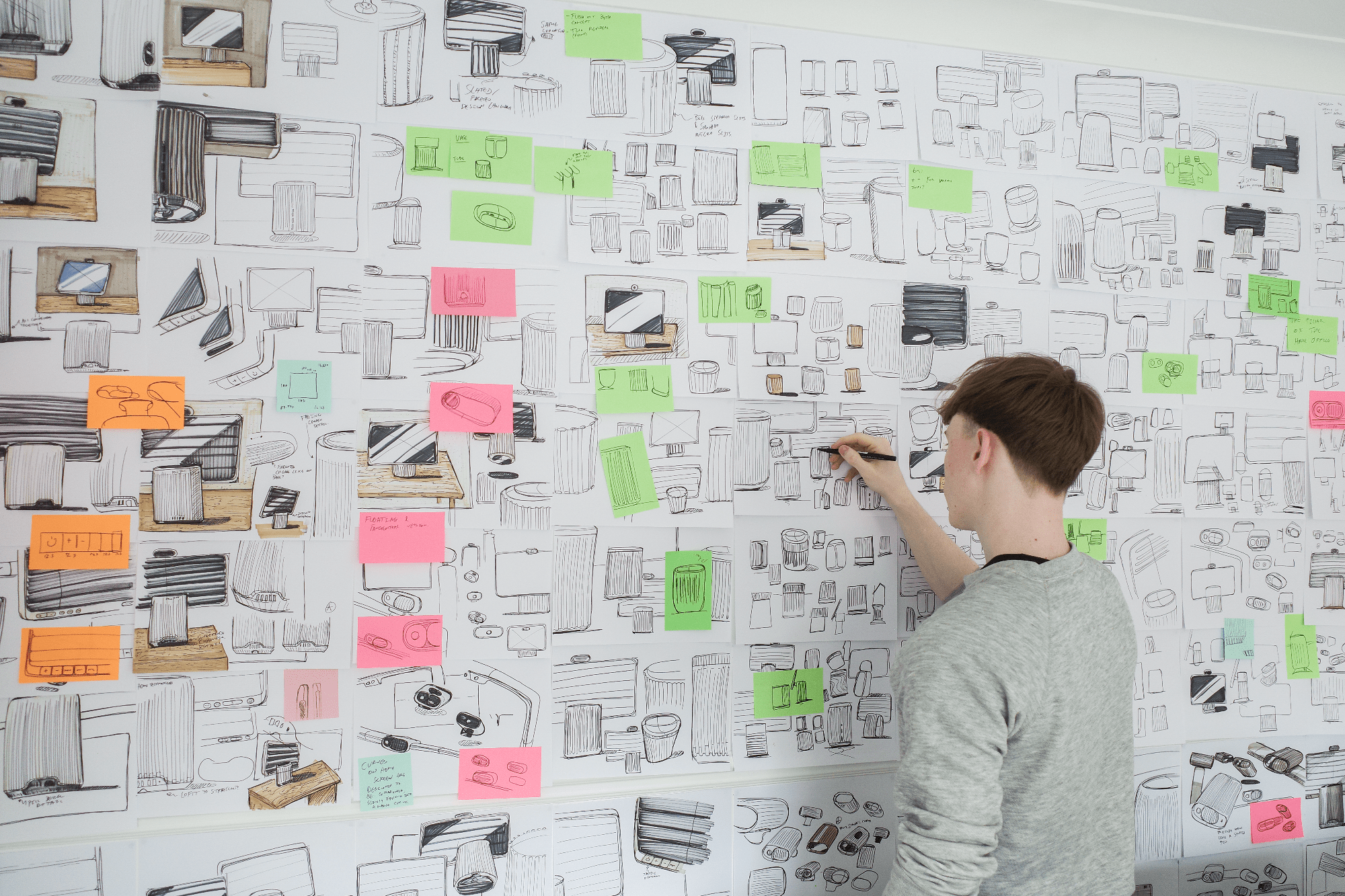 HomeTechCo designer sketching product concepts on a white board filled with drawings and colourful sticky notes