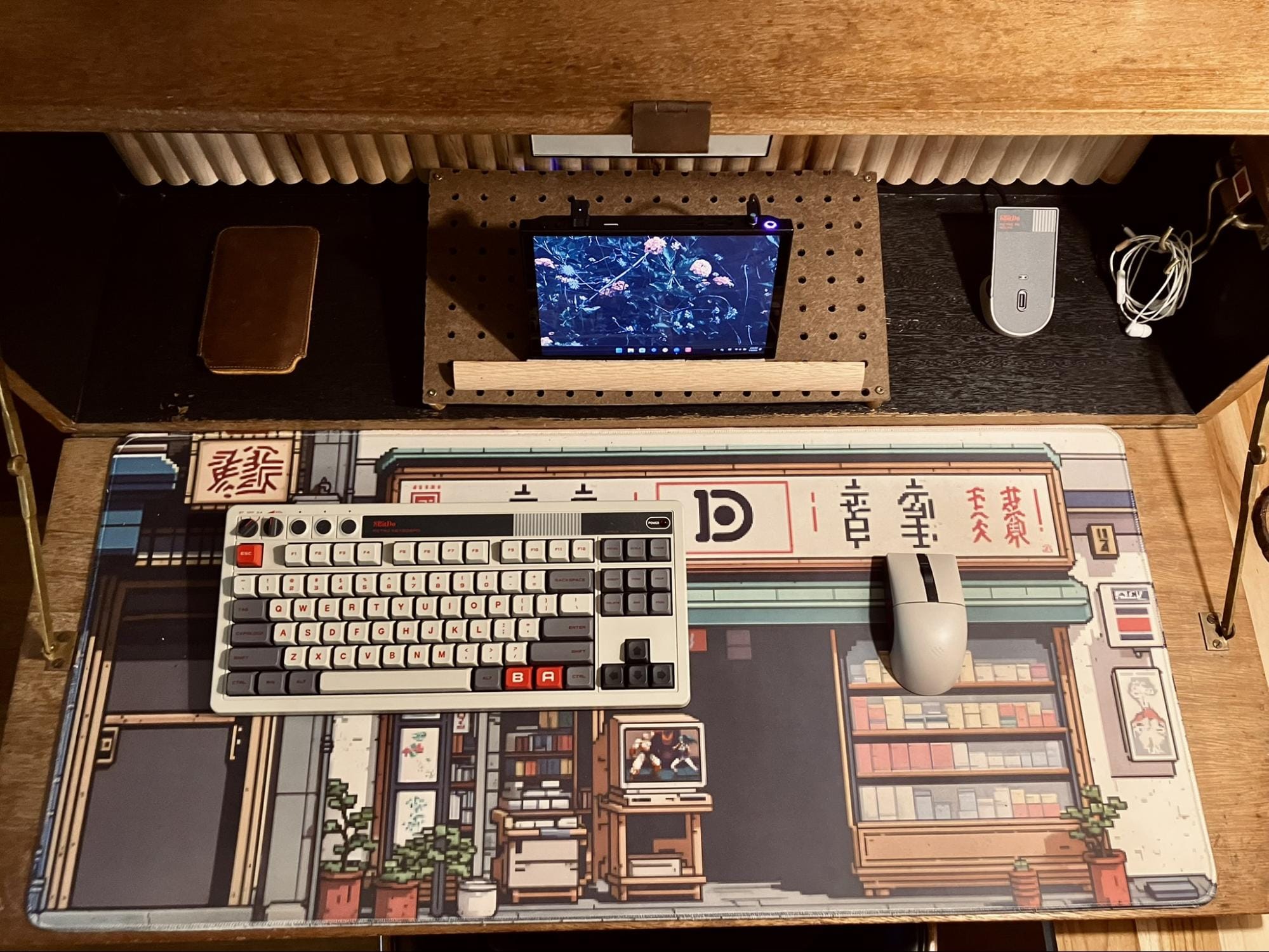 overhead view of minimalist retro desk setup with mechanical keyboard, wireless mouse, Lenovo Legion Go handheld PC, and the Pixel Palace Deskpad