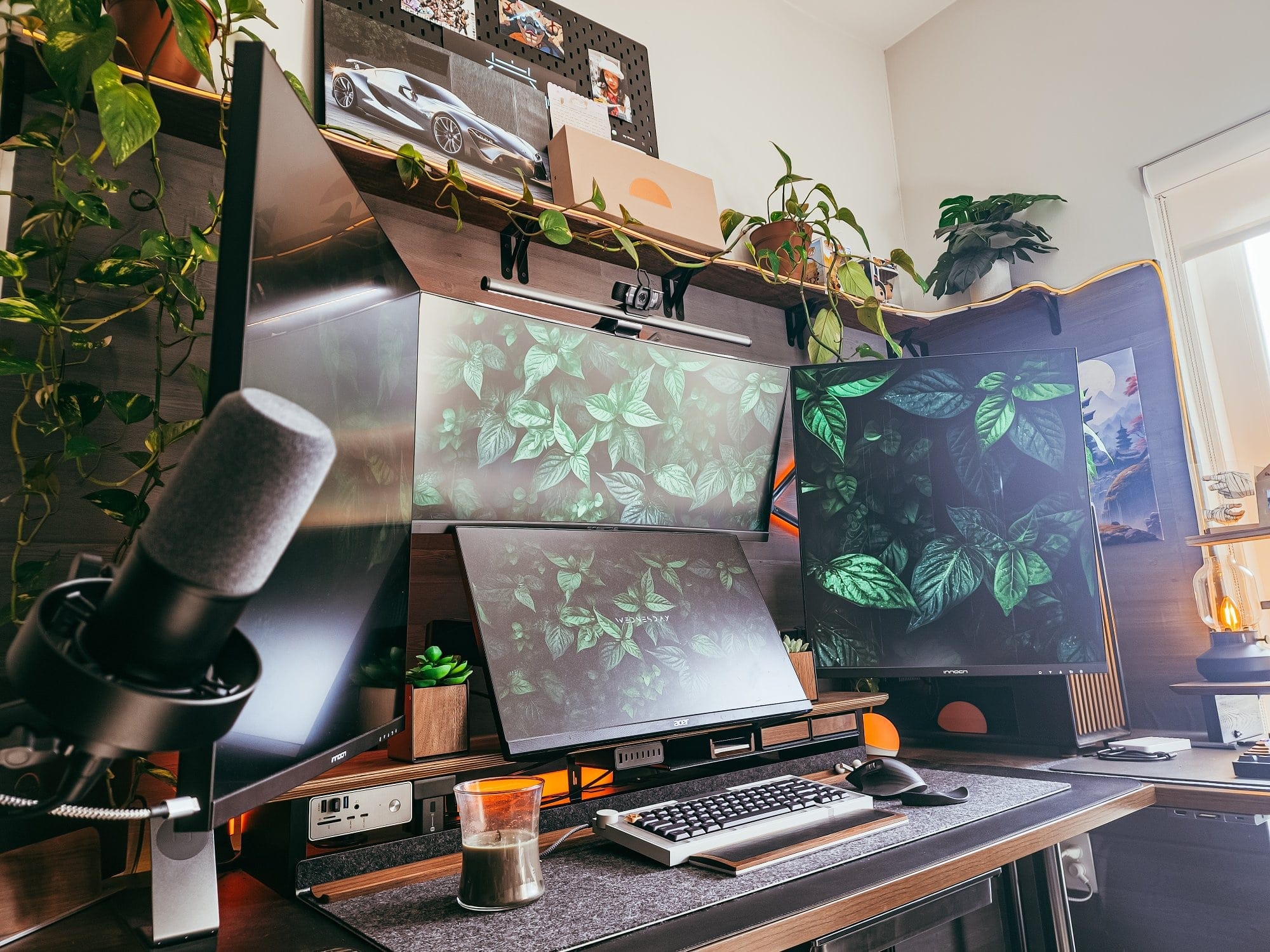 modern desk setup with four monitors, mechanical keyboard, streaming microphone, custom pc, indoor plants, and ambient lighting