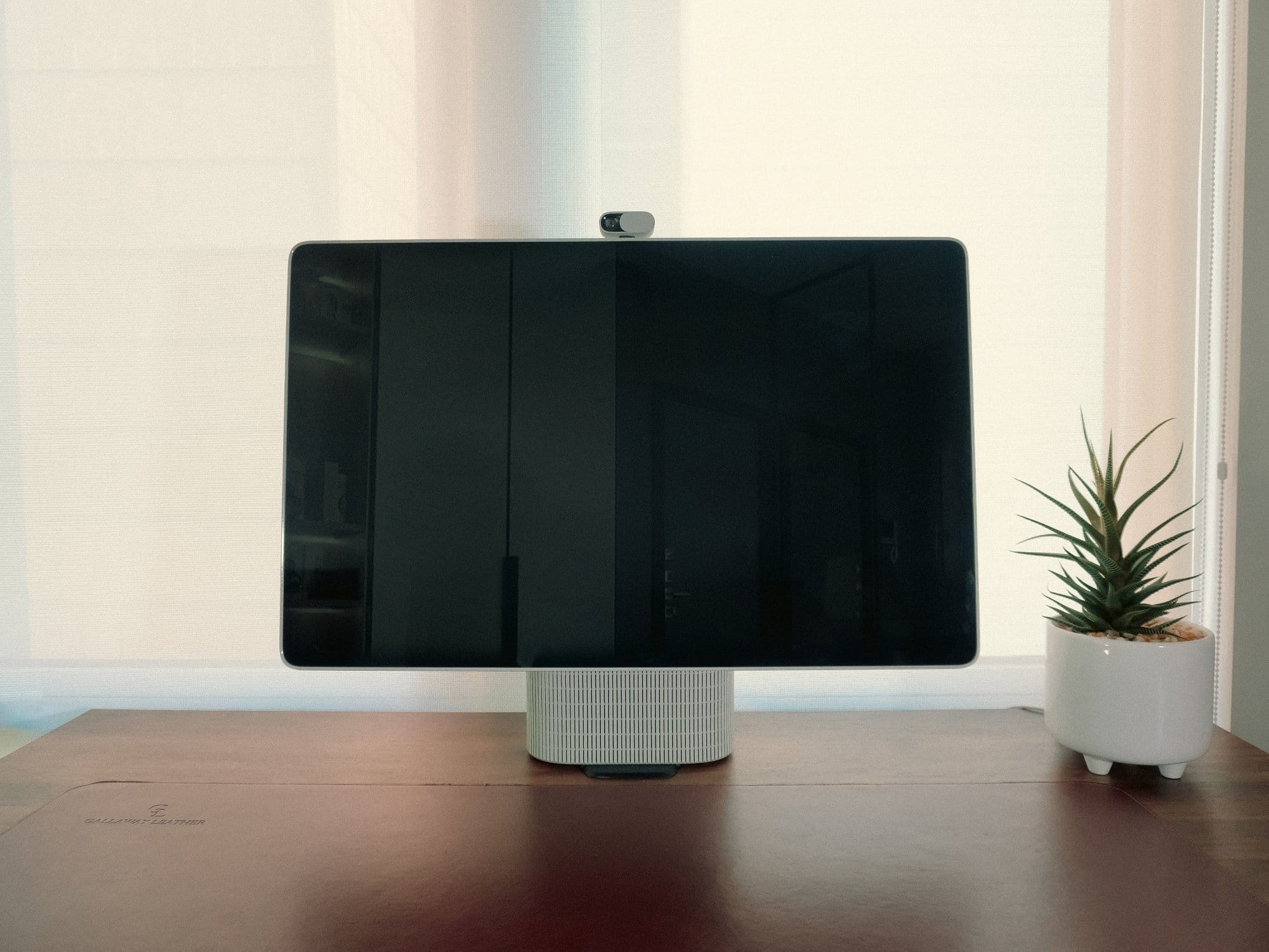 close-up of the HomeTechCo Home Display on a desk with a leather mat and small potted plant