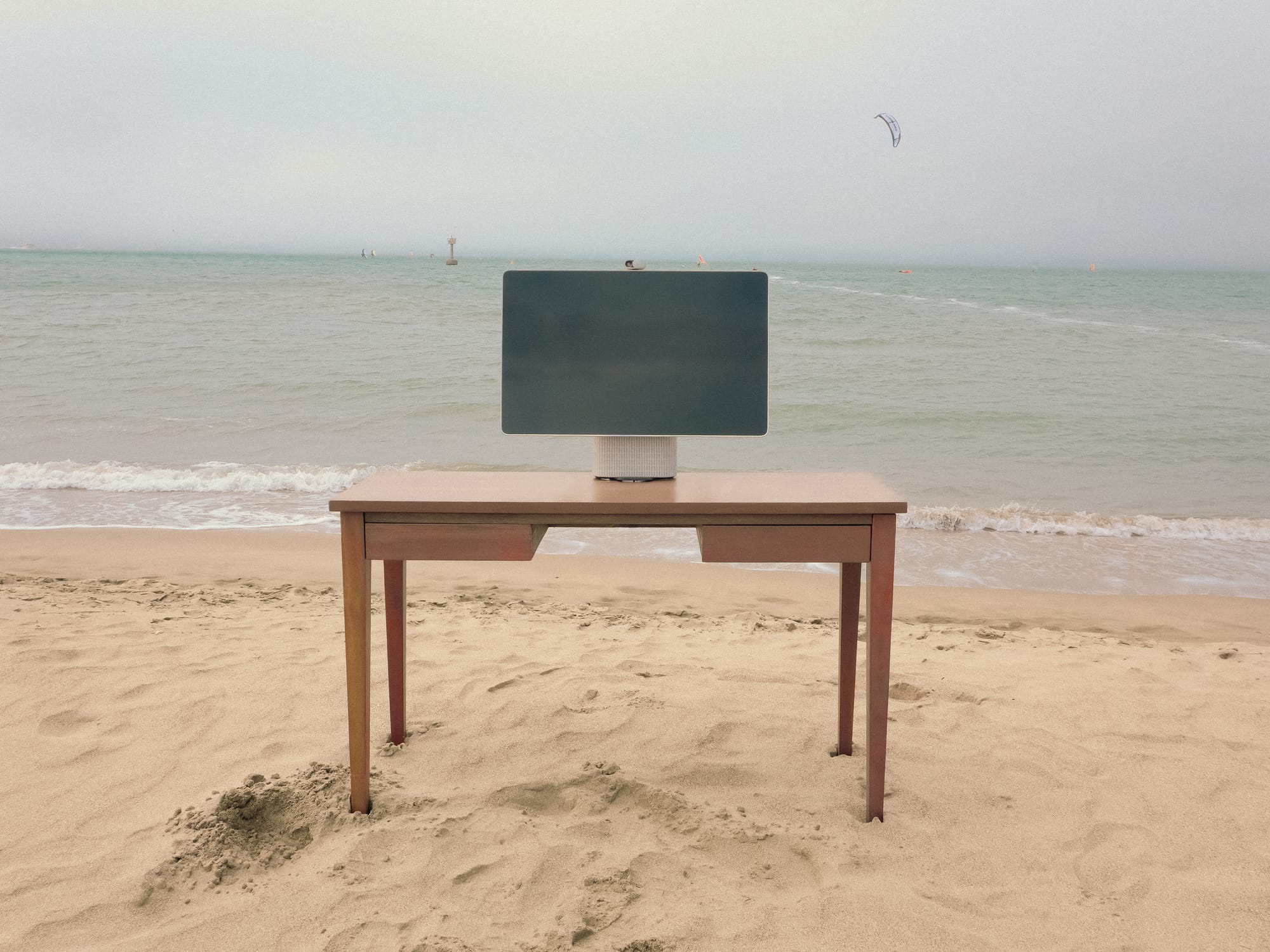 HomeTechCo Home Display set up on a wooden desk at the beach with the ocean in the background
