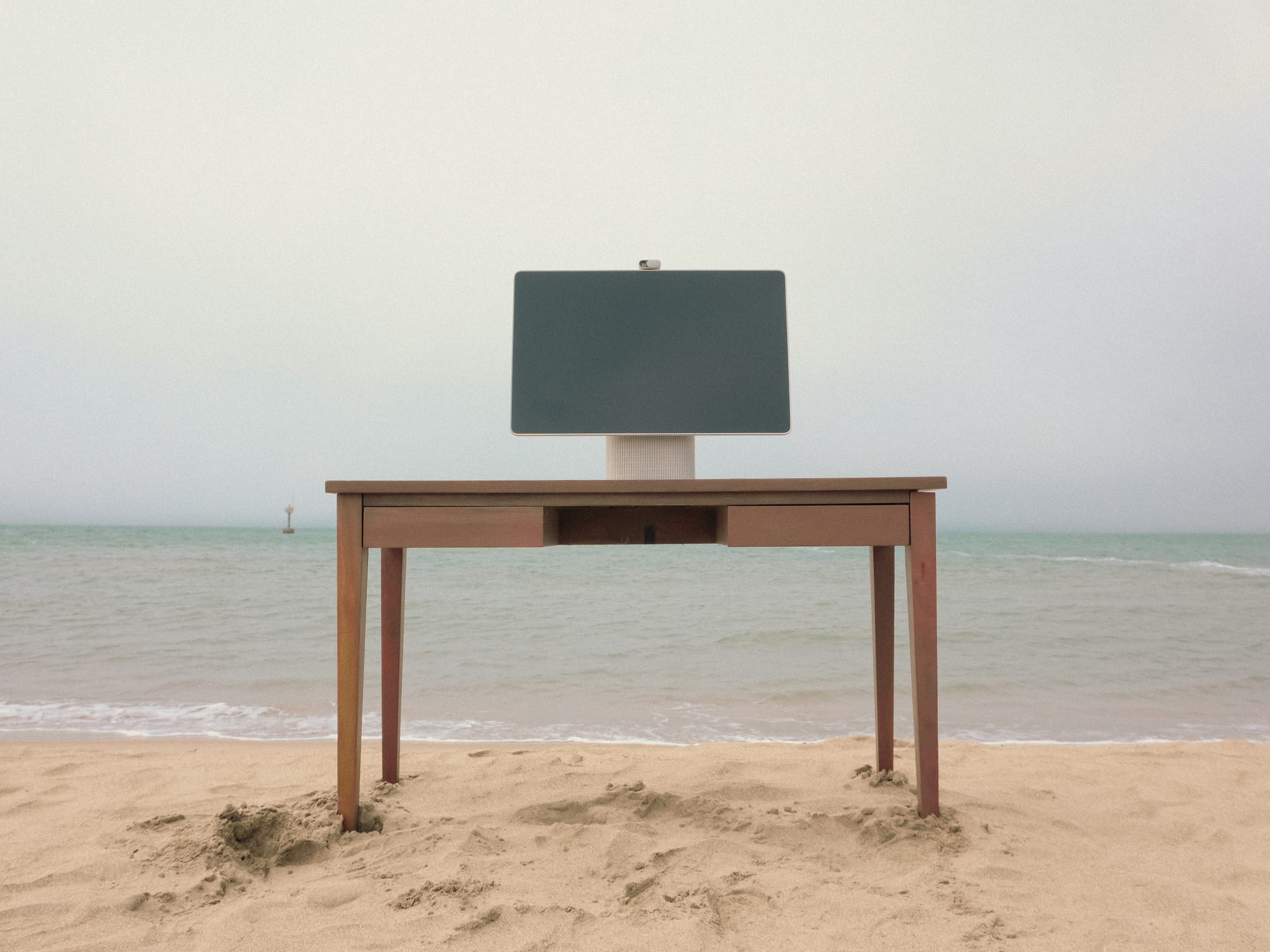 HomeTechCo Home Display set up on a wooden desk at the beach with the ocean in the background
