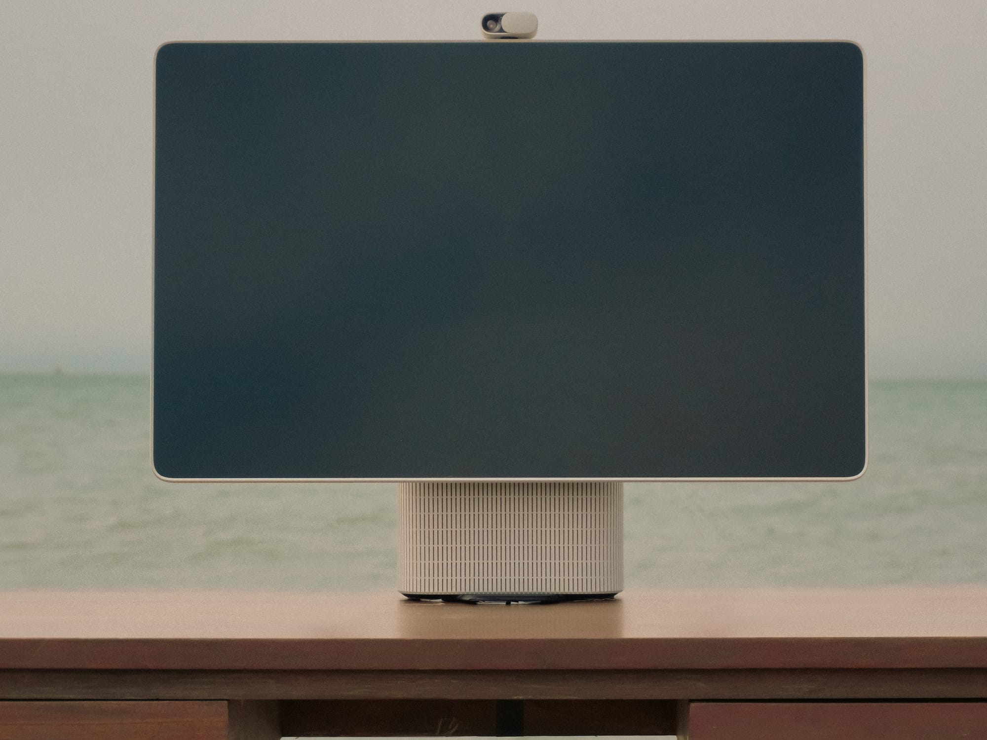 close-up of the HomeTechCo Home Display on a wooden desk with the ocean in the background